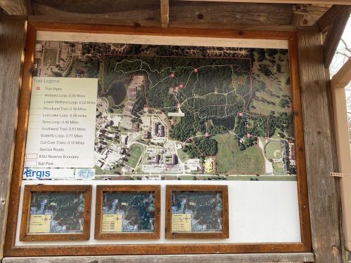 Map of a trail system with routes and distances, displayed on a wooden board with information about the area.