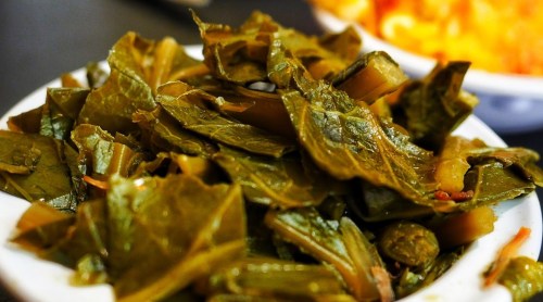 A close-up of a bowl filled with cooked green leafy vegetables, showcasing their vibrant color and texture.