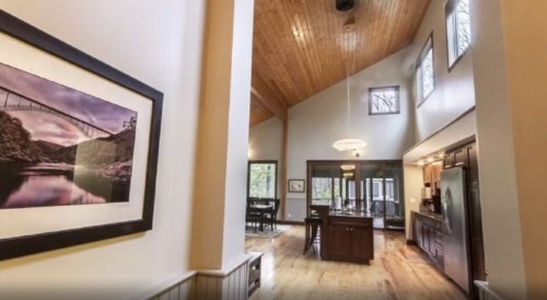 Interior view of a spacious, modern home with high ceilings, wooden accents, and a large kitchen area.