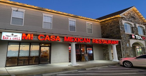 Exterior of Mi Casa Mexican Restaurant at dusk, featuring bright signage and a welcoming entrance.