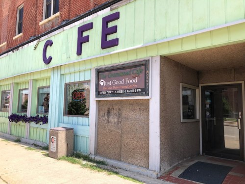 Exterior of a restaurant with a green facade and a sign reading "Just Good Food," open daily from 6 AM to 2 PM.