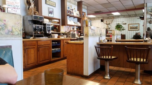 A cozy diner interior with wooden furniture, a counter, and a coffee station, featuring a warm, inviting atmosphere.