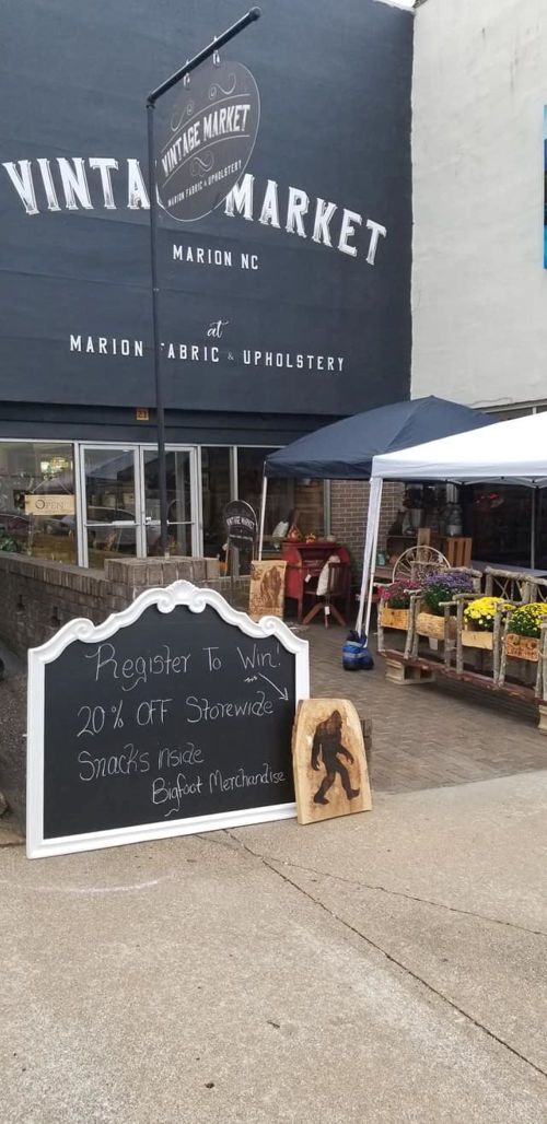 A storefront with a sign advertising a sale, snacks, and a Bigfoot merchandise display outside.