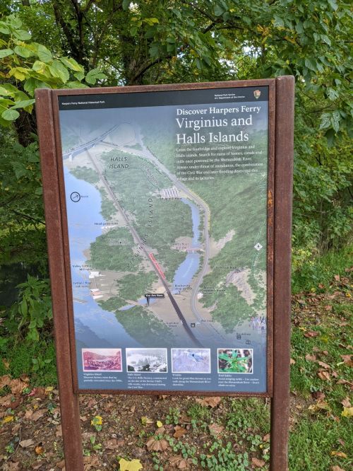 Map sign for Harpers Ferry, highlighting Virginius and Halls Islands, surrounded by trees and natural scenery.