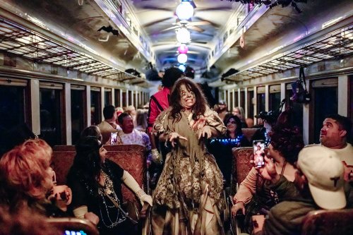 A spooky performance on a decorated train, with costumed characters entertaining a captivated audience.