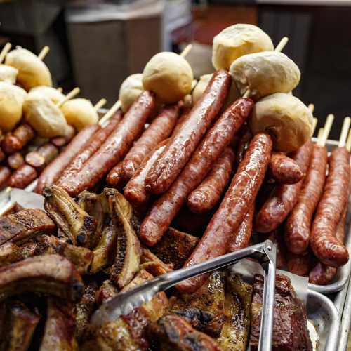 A variety of grilled sausages and rolls arranged on a platter, showcasing a delicious assortment of meats.