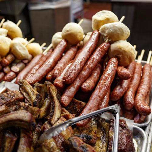 A variety of grilled sausages and rolls arranged on a platter, showcasing a delicious assortment of meats.