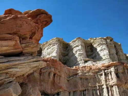 Rocky cliffs with layered formations under a clear blue sky.