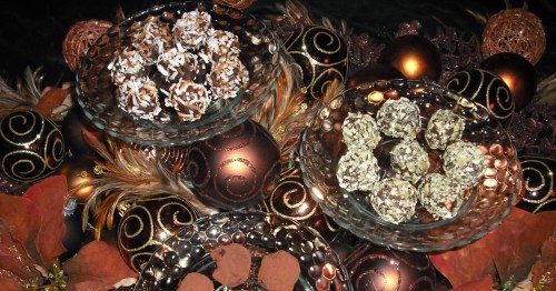 Three glass bowls filled with assorted chocolate truffles, surrounded by decorative ornaments and autumn leaves.