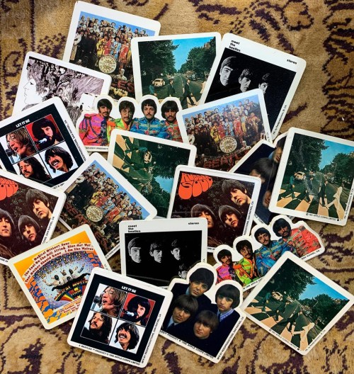 A collection of vintage Beatles album covers and promotional photos scattered on a patterned surface.