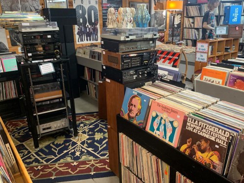 A cozy record store filled with vinyl records, audio equipment, and colorful album covers on display.