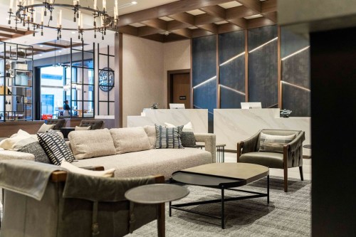 Modern lobby with a cozy seating area, stylish decor, and a reception desk in the background.