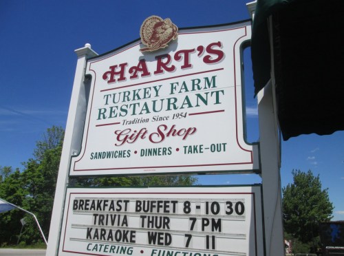 Sign for Hart's Turkey Farm Restaurant, featuring dining options, gift shop, and event details like trivia and karaoke nights.