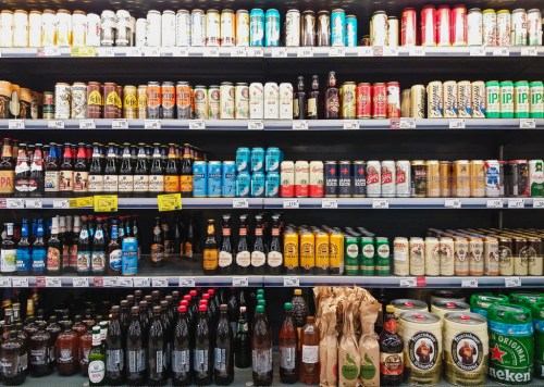 A variety of beer bottles and cans displayed on shelves in a store, featuring different brands and styles.