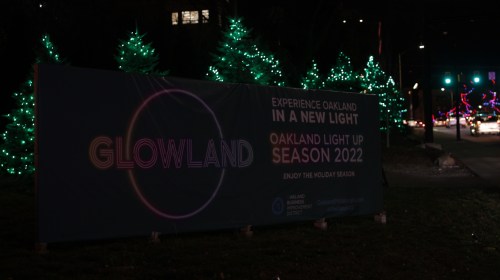 A banner for "Glowland" promoting Oakland's holiday light season, with illuminated trees in the background.