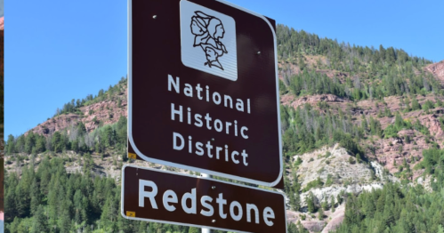 Sign for the National Historic District in Redstone, surrounded by green mountains and clear blue sky.