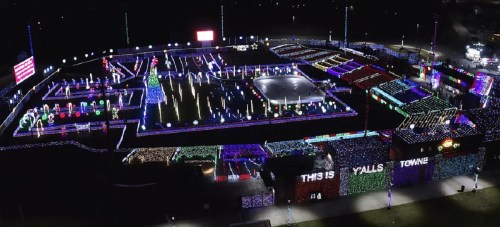 Aerial view of a festive display featuring colorful holiday lights, an ice skating rink, and decorated structures.