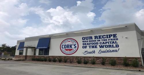 Exterior of Cork's restaurant with a sign stating "Our recipe was born in the fried seafood capital of the world - South Louisiana!"