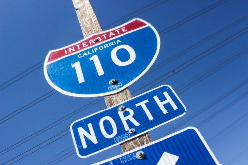 Interstate 110 North sign in California against a clear blue sky.
