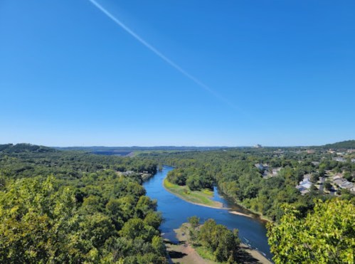 A scenic view of a winding river surrounded by lush green trees under a clear blue sky.