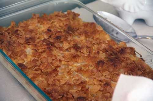 A baked dish topped with golden, crispy cornflakes in a glass baking dish.