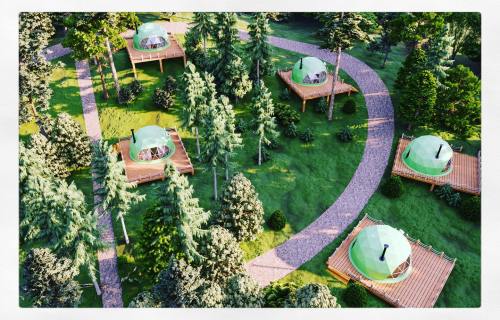 Aerial view of eco-friendly dome cabins on wooden platforms, surrounded by trees and a winding path.