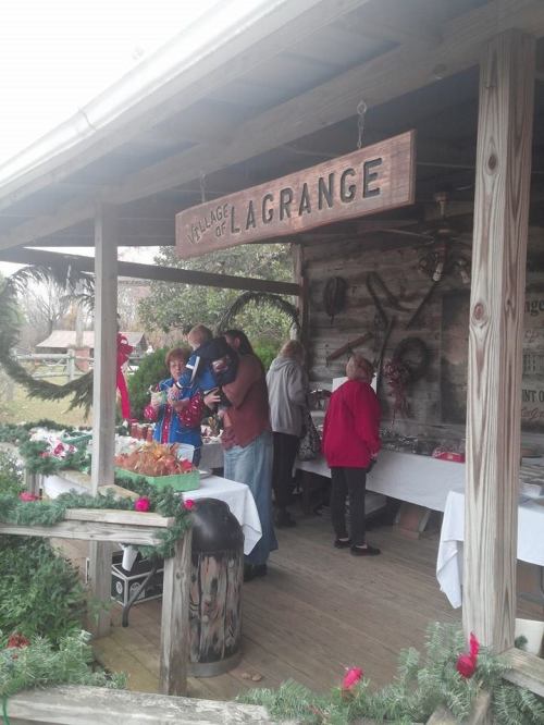 People browsing a rustic market stall at the Village of Lagrange, decorated for the holidays.