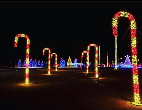 Colorful candy cane lights illuminate a festive scene at night, surrounded by various holiday decorations.