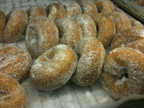 A close-up of freshly made, sugar-coated donuts arranged on a tray.