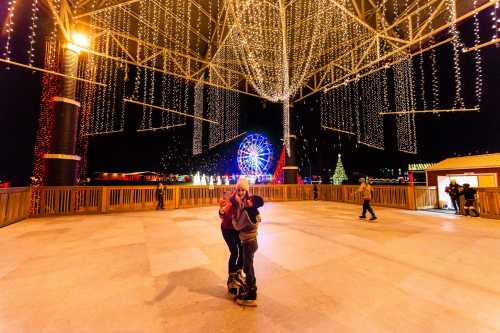 A couple embraces on an ice rink surrounded by festive lights and a Ferris wheel in the background.