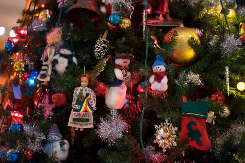 A festive Christmas tree adorned with colorful ornaments, dolls, snowmen, and twinkling lights.