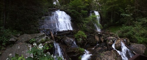 A scenic view of cascading waterfalls surrounded by lush greenery and rocky terrain.
