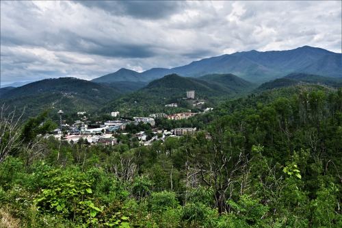 A panoramic view of a mountainous landscape with a town nestled in the valley, under a cloudy sky.