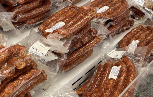 A display of vacuum-sealed sausages in various shapes and sizes, arranged neatly in a cooler.