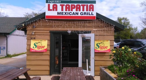 Exterior of La Tapatia Mexican Grill, featuring a wooden building, sign, and outdoor seating area.
