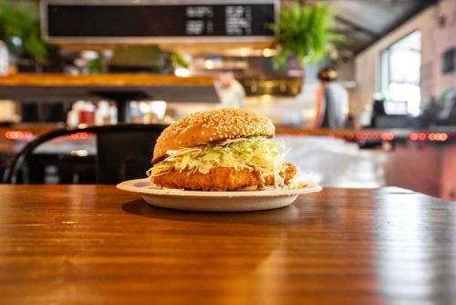 A sesame seed bun sandwich with crispy chicken and shredded lettuce, placed on a plate on a wooden table.