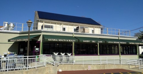 Exterior view of Whole Earth Center featuring a bakery, deli, and natural health store, with solar panels on the roof.