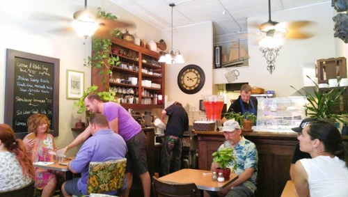 A cozy café scene with patrons enjoying drinks, a barista at work, and plants decorating the space.