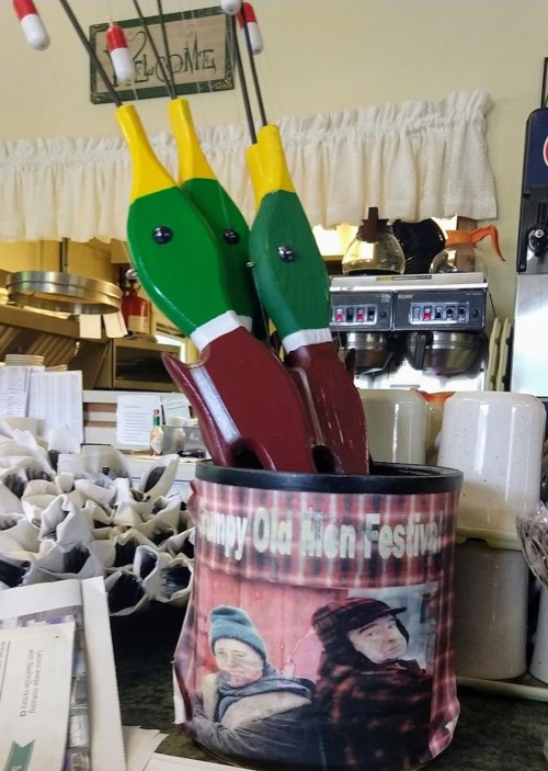 A decorative container featuring a photo of two men, holding colorful duck decoys, sits on a counter.