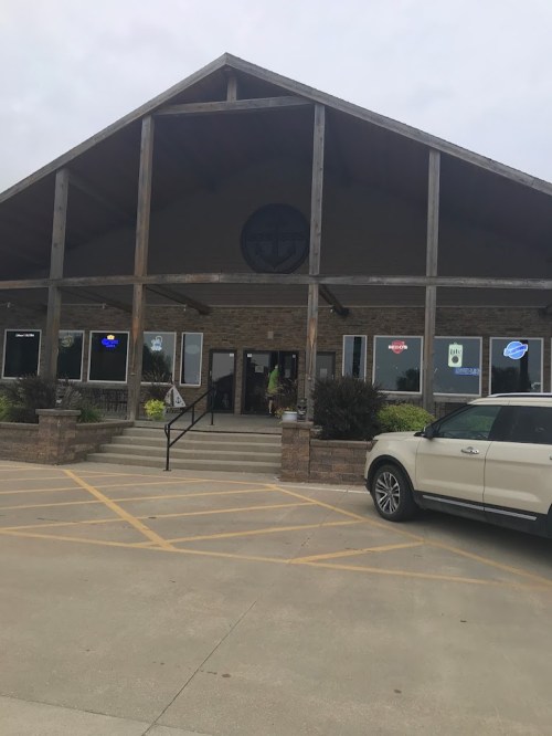 A large, rustic building with a wooden facade and a stone base, featuring multiple windows and a welcoming entrance.