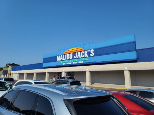 Exterior of Malibu Jack's, an entertainment center with a bright blue facade, featuring "Now Open" signage.
