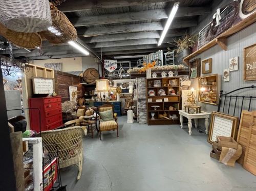 A cozy vintage shop filled with various antiques, furniture, and decor items in a rustic setting.