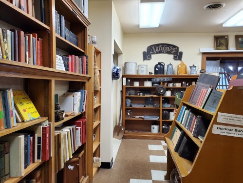 A cozy interior of a bookstore with wooden shelves filled with books and antiques displayed on the walls.