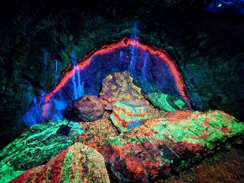 A vibrant cave scene with glowing rocks and colorful lighting, creating a surreal, otherworldly atmosphere.