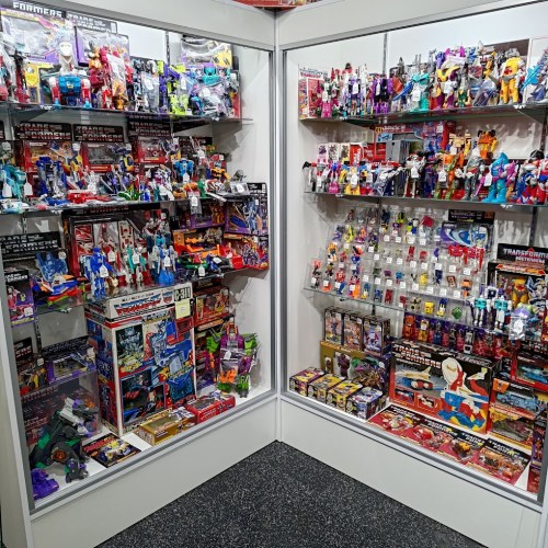 A display case filled with various Transformers toys and collectibles, showcasing vibrant packaging and figures.