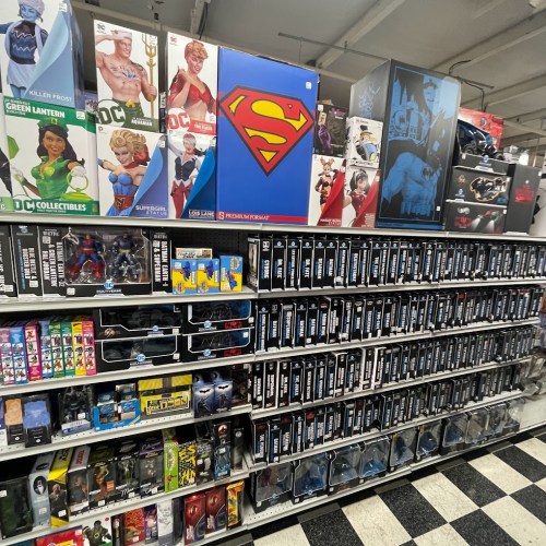 A store display featuring various superhero action figures and collectibles, including Superman and Batman merchandise.