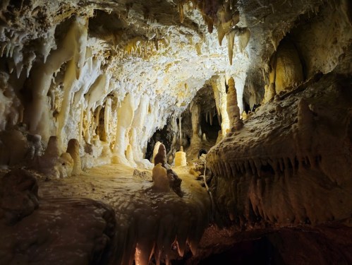 A stunning cave interior with stalactites and stalagmites illuminated by soft lighting, creating a mystical atmosphere.