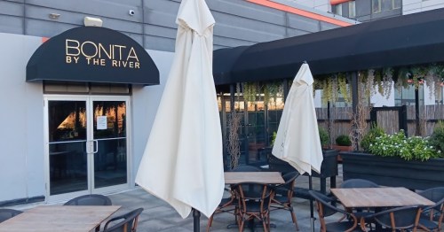 Exterior of Bonita by the River restaurant, featuring outdoor seating and large umbrellas.