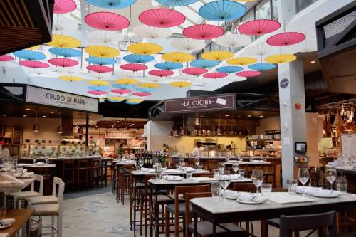A vibrant restaurant interior with colorful umbrellas hanging from the ceiling and tables set for dining.