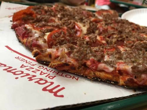 A close-up of a pizza topped with pepperoni and sausage on a pizza box.